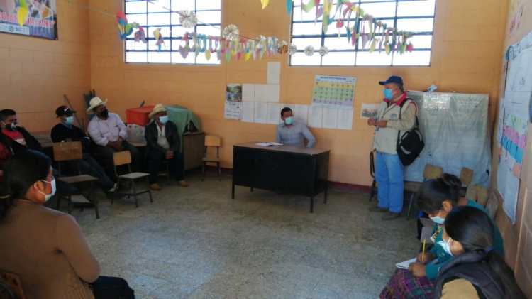 A group of people wearing masks sitting in a room in a discussion